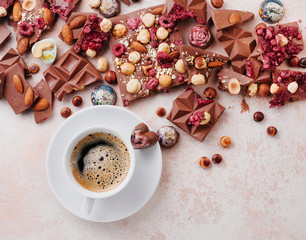 Cup of coffee with pieces of milk chocolate with nuts and chocolate candies