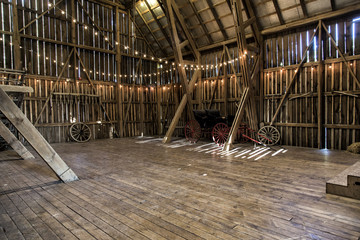 The interior of a barn with strings of lights and a buggy