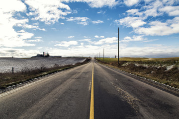Fototapeta na wymiar Farm fields surround a long, empty country road