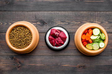 Ingredients for dry pet food. Meat and vegetables zucchini and carrot on dark wooden backgroud top view copy space