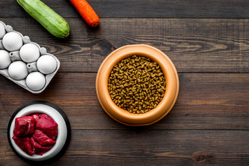 Dry food for dogs and cats based on raw meat and vegetables on dark wooden backgroud top view copy space