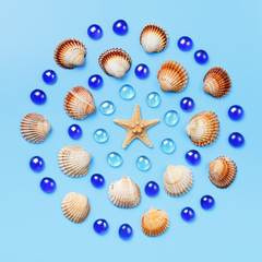 Pattern of seashells, starfish, and blue glass beads on a light blue background.