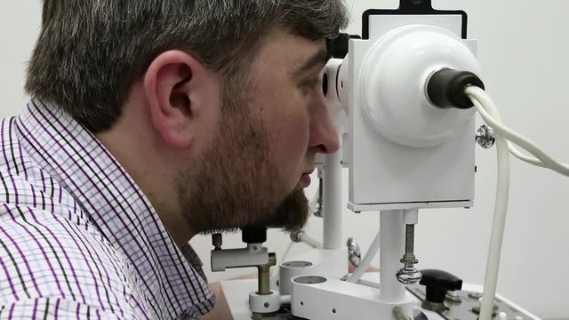 Patient in ophthalmology clinic. Man looks in synoptophore - ophthalmic instrument, used for diagnosing imbalance of eye muscles and treating them by orthoptic methods, for treatment of strabismus