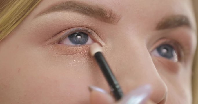 Painting eye with eyeshadows, closeup makeup, professional visagist