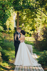 Confident elegant groom and beautiful shy bride holding hands ou