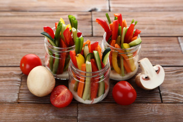 Sliced vegetables in glasses on brown wooden table