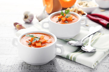 Pumpkin soup with seeds and parsley in plate on wooden table