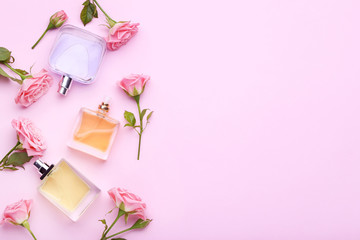 Perfume bottles with flowers on pink background