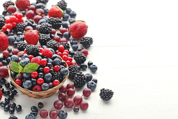 Ripe and sweet berries in basket on white wooden table