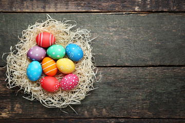 Colorful easter eggs in nest on wooden table