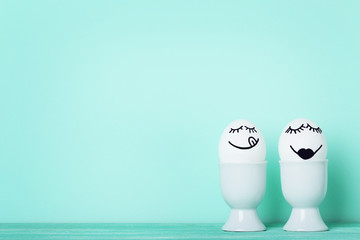 Eggs with funny faces on mint background