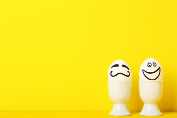 Eggs with funny faces on yellow background