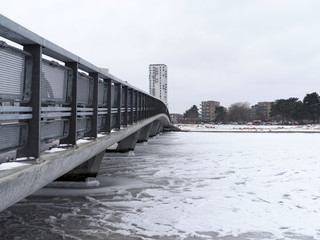 Small bridge across frozen canal at amager beach, covered in snow