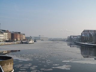 Obraz premium River/harbor in city with ice floes, blue sky and colored buildings