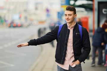 Young man trying to stop the car on the street and rise his hand