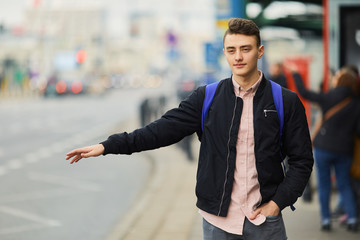 Young man trying to stop the car on the street and rise his hand
