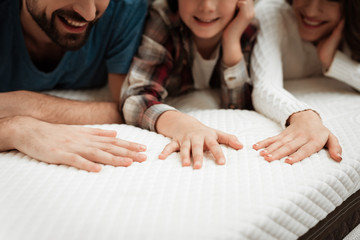 Young couple together with their young son test material of mattress for a touch. - obrazy, fototapety, plakaty