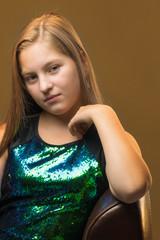 A teenage girl is sitting on a leather chair.