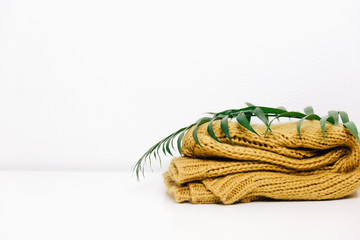 Obraz premium Knitted warm yellow sweater with tropical green leaf