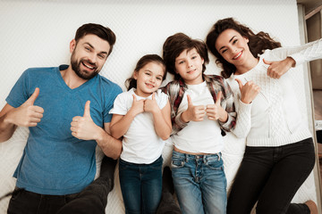 Happy family enjoying of comfort lies on mattress inside furniture store.