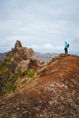 Naklejka premium Traveler with backpack looking over the mountain peaks. Stunning arid landscape of Santo Antao island, Cabo Verde