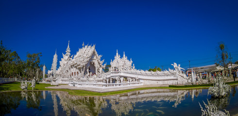 Panoramic view of white church of Wat Rong Khun temple in Chiangrai, Thailand, reflected in the water