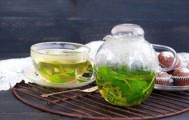 Kettle and a cup of herbal tea with mint and lemon thme, chocolate muffins with coconut
