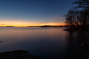 Obraz premium sunset at a lake with trees on the side and boats on the horizon