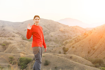 Girl tourist affably waving in the steppe mountains
