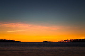 Fototapeta premium beautiful sunset at the sea with trees on the horizon