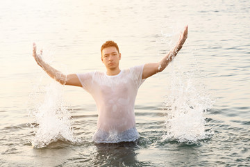 A handsome man stands in the water and creates two spray posts