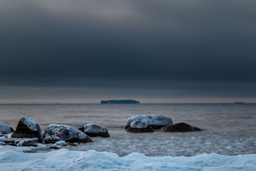 Fototapeta na wymiar snow and ice on stones at the coast