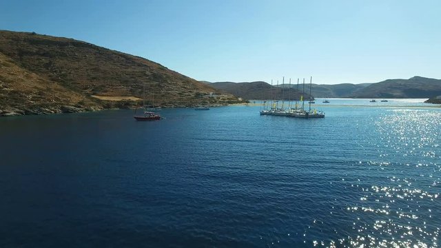 Roped yachts regatta anchored in the Gulf of the Mediterranean Sea near the Kolona beach. Eight luxury yachts are connected by a rope. Linked yachts in bright sunny day near Apokrisi, Kithnos, Greece