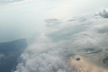 View from the airplane window to the clouds and the relief of the earth 