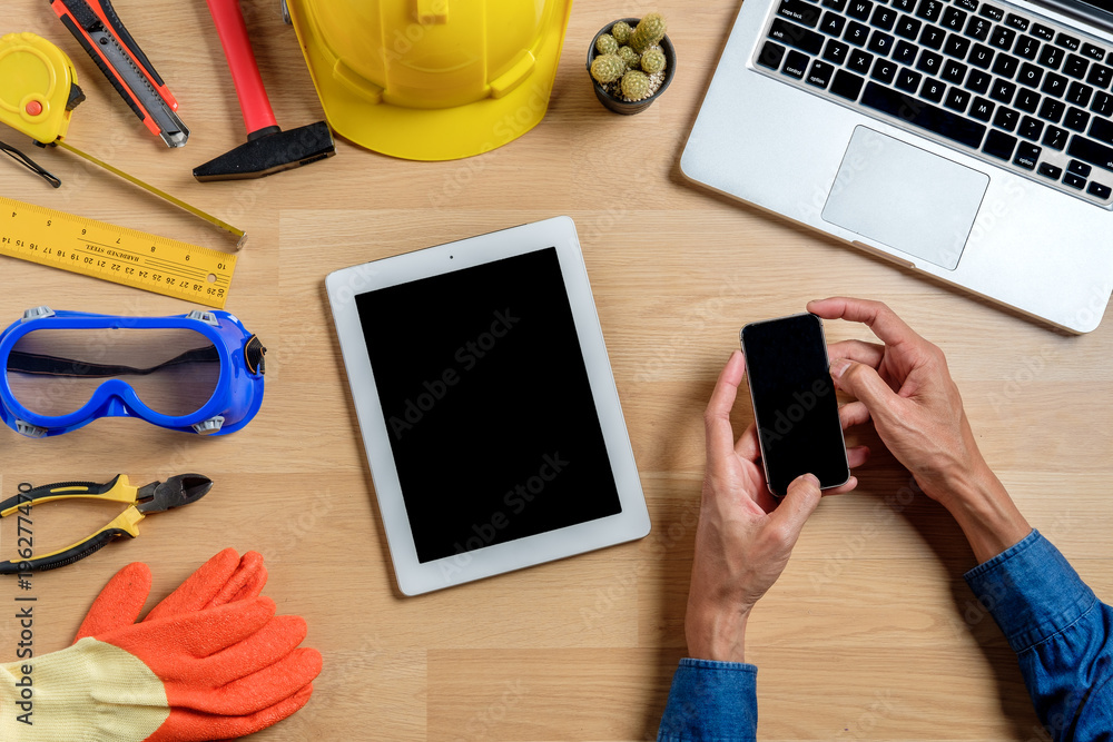Poster engineer man using smart phone in hands touching on a screen and he is sitting on office.view from a