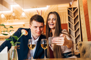 Happy young couple taking selfie with smart phone at cafe