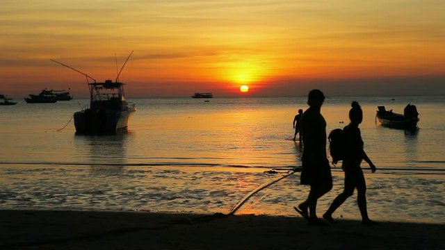 tourist walking on sea beach against beautiful sunset sky