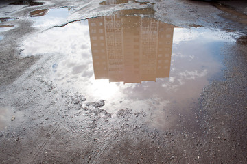 The bad asphalted road with a big pothole filled with water. Dangerous destroyed roadbed.