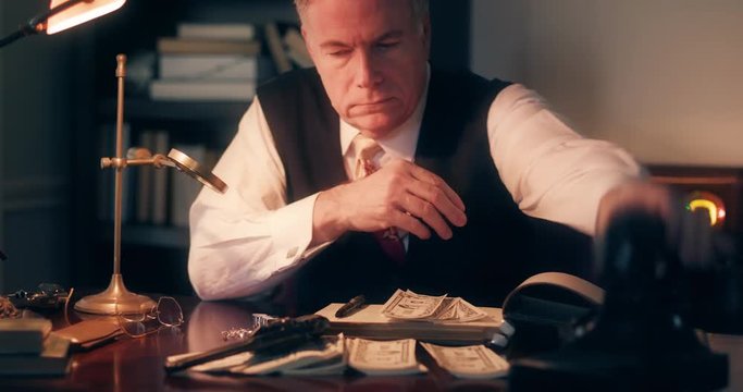 A 1940s mobster type accountant lays down the money he is counting takes a brief phone call then checks the revolver that is laying on his desk.