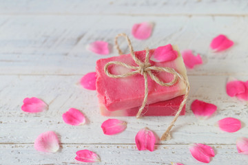Soap with Rose Extract.Handmade soap with rose extract and rose petals on white wooden plank background. Organic Vegetable Cosmetics Concept.vegan soap with rose fragrance