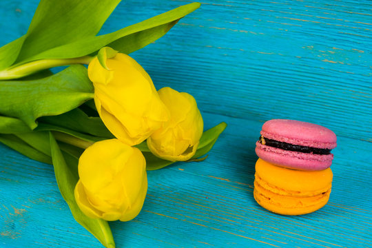 yellow tulips with macaroons on turquoise wooden table