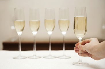 Hand holding a glass of champagne against row of glasses