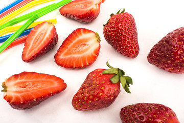 Strawberries and straws scattered on a white background