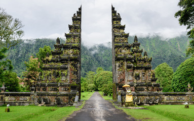 Candi Bentar is a classical Javanese and Balinese gateway entrance, Bali, Indonesia. After the rain, the mountains are misted.