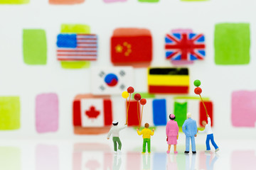 Miniature people: family group standing with flag international for background. Image use for learning, education concept.