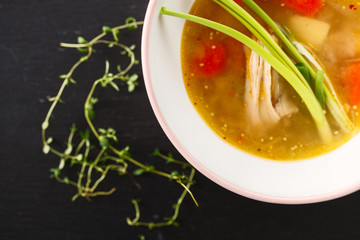 homemade chicken soup in white plate on black background