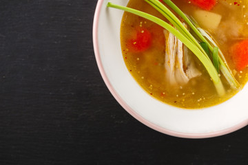 homemade chicken soup in white plate on black background