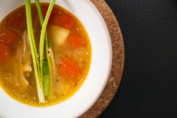 homemade chicken soup in white plate on black background