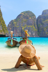 Young woman sitting on the beach at Maya Bay on Phi Phi Leh Island, Krabi Province, Thailand. Koh...