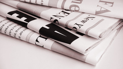 News in headlines of daily papers. Folded newspapers for background
